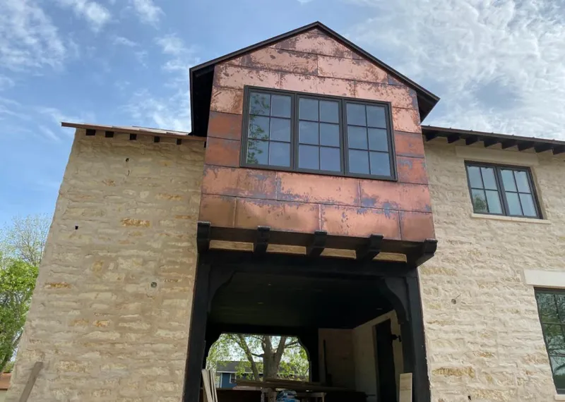 Copper metal panel facade on a stone building for Roof Repair in Warren