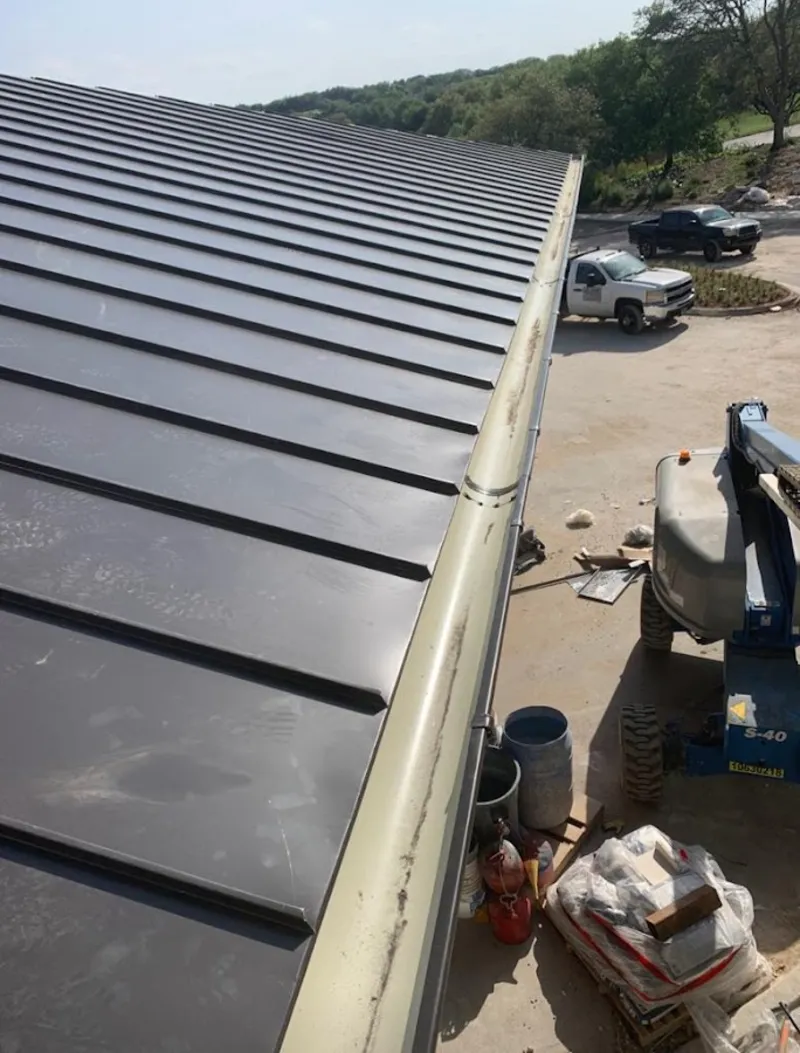 Standing seam panel and gutter detail on a metal roofing jobsite in Warren